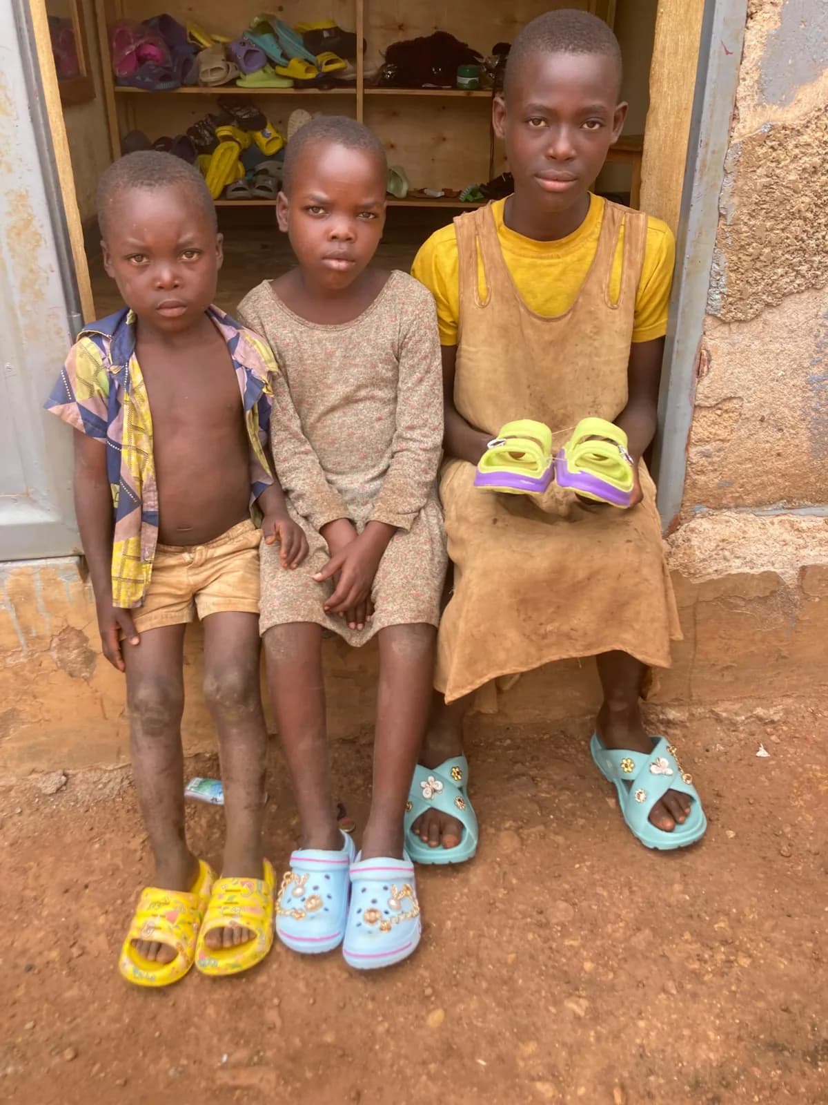 Three children at a doorway with new sandals