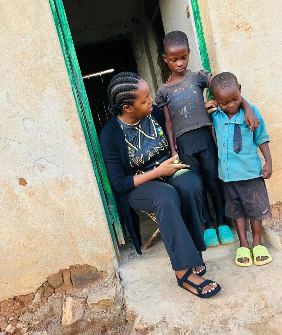 An adult sitting with two children outside a home