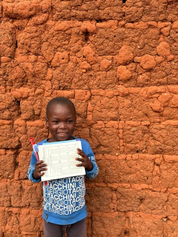 A child holding a book against an earthen wall